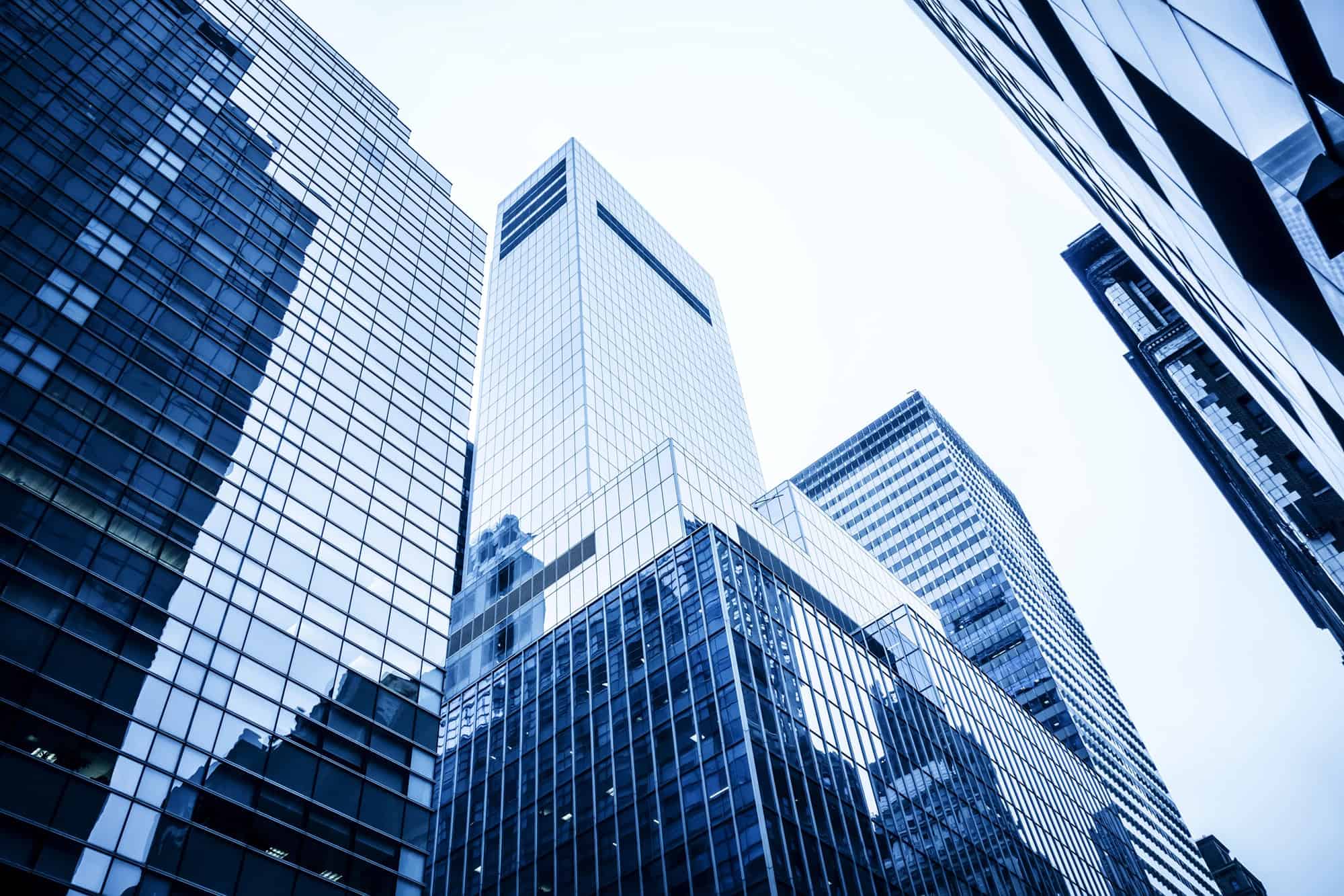 View looking up at tall, modern glass skyscrapers against a bright sky in a cityscape, reflecting the ambition of finance leaders and the evolving CFO role.