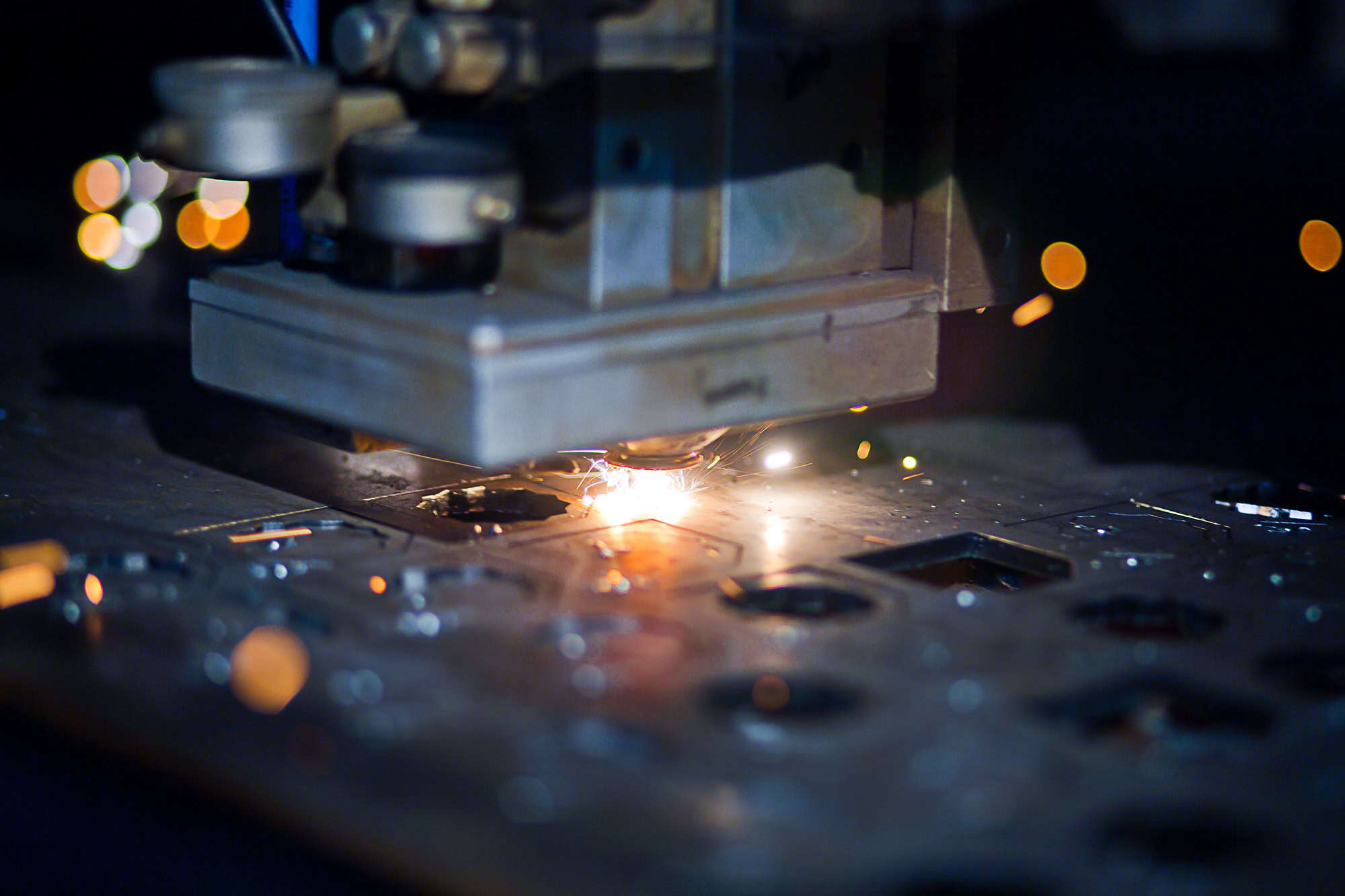 A close-up of a CNC laser cutting machine precisely shaping metal sheets, with sparks flying—a glimpse into advanced industrial manufacturing trends projected for 2025.